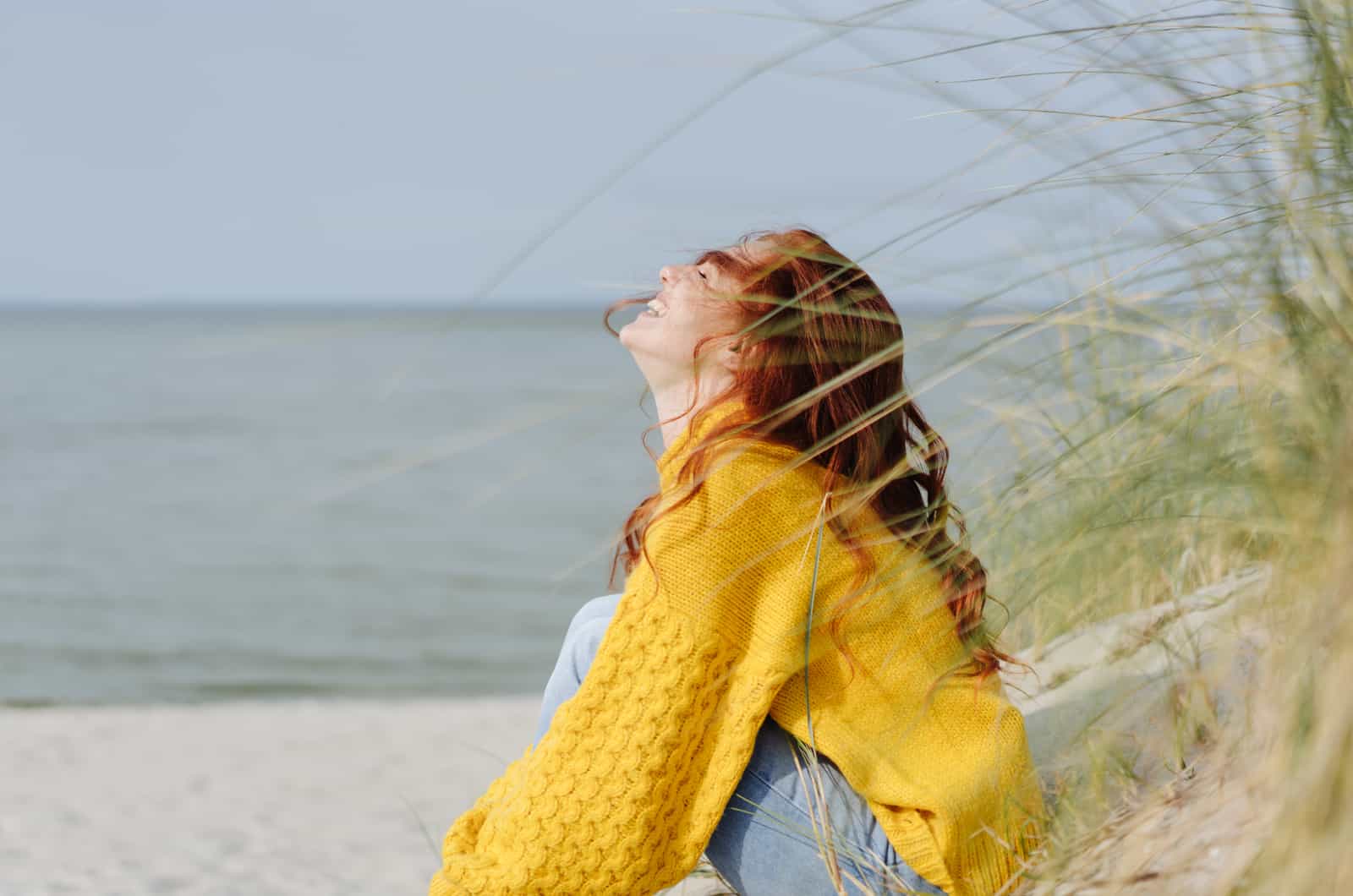 happy woman in yellow sitting on beach