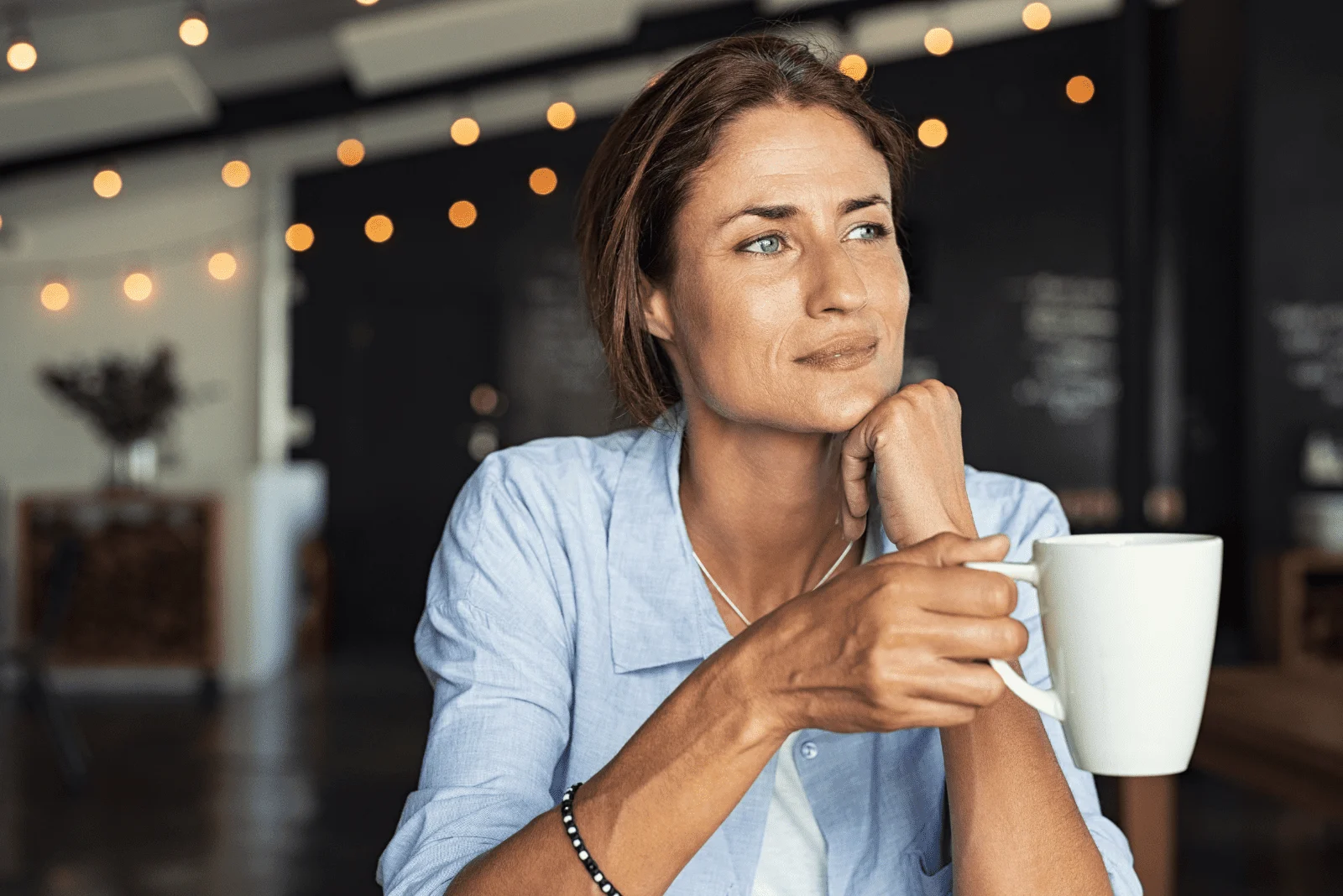 pensive woman sits with a cup in her hand