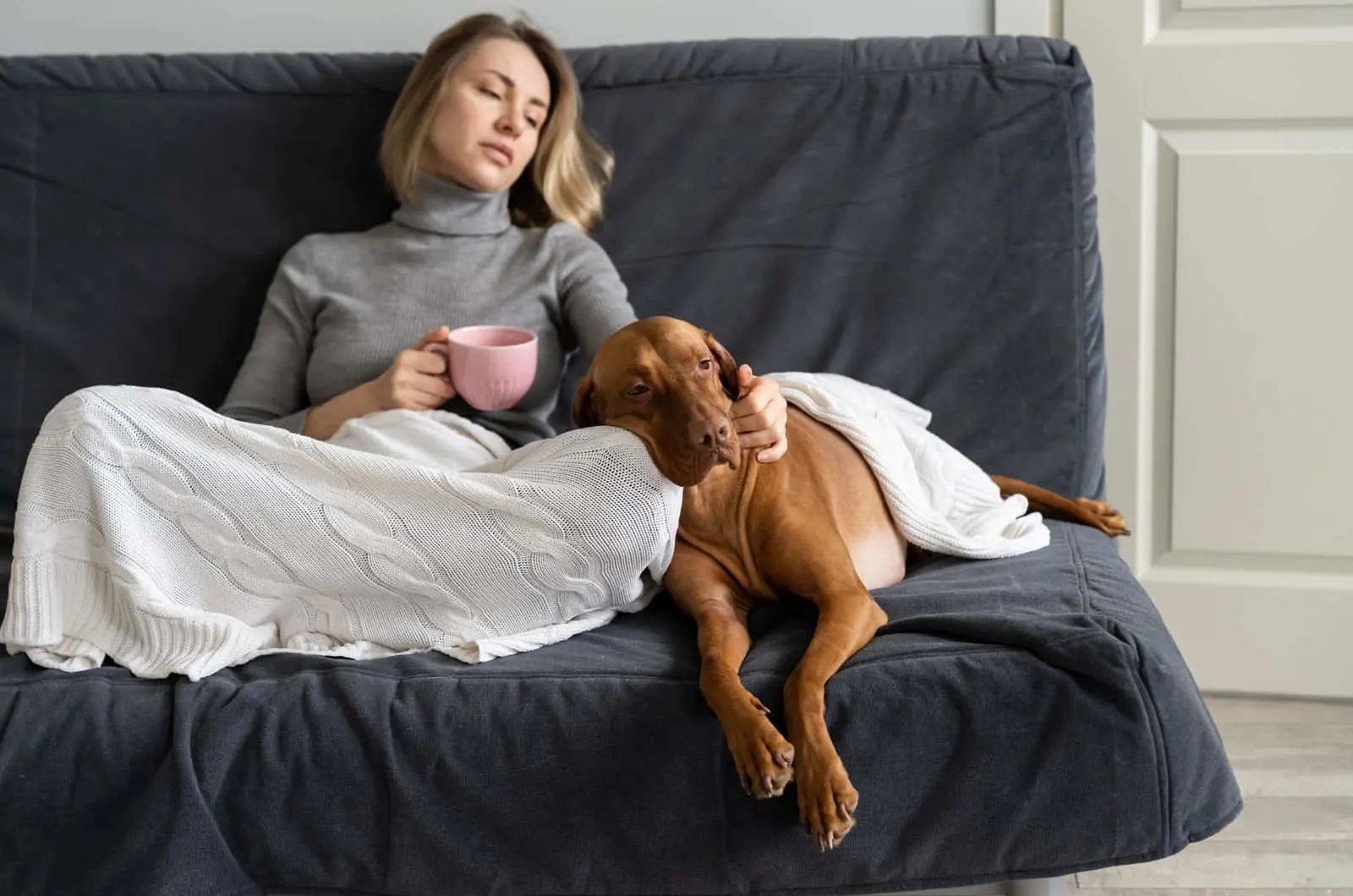 sick woman sitting on sofa with her dog