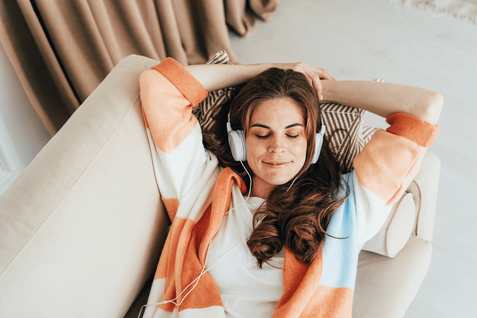 woman lies in bed and listens to music