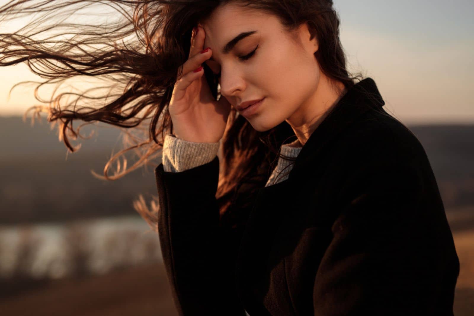 giovane donna sola ed esausta con i capelli lunghi che svolazzano al vento