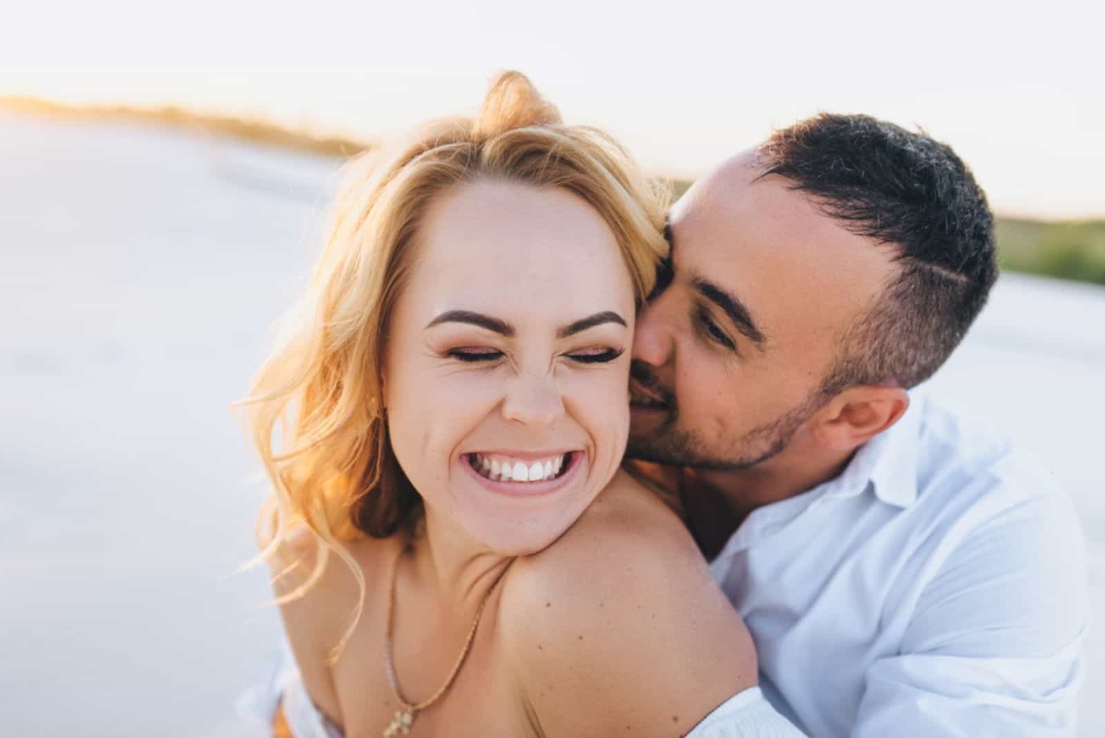 hombre besando hermosa mujer sonriente en la cabeza