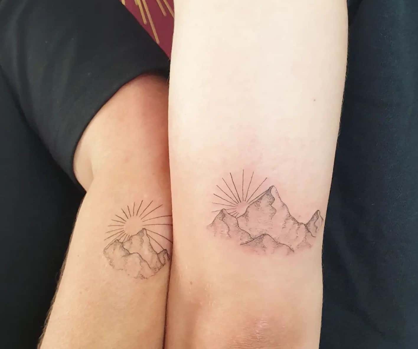 Il sole dietro il tatuaggio delle montagne