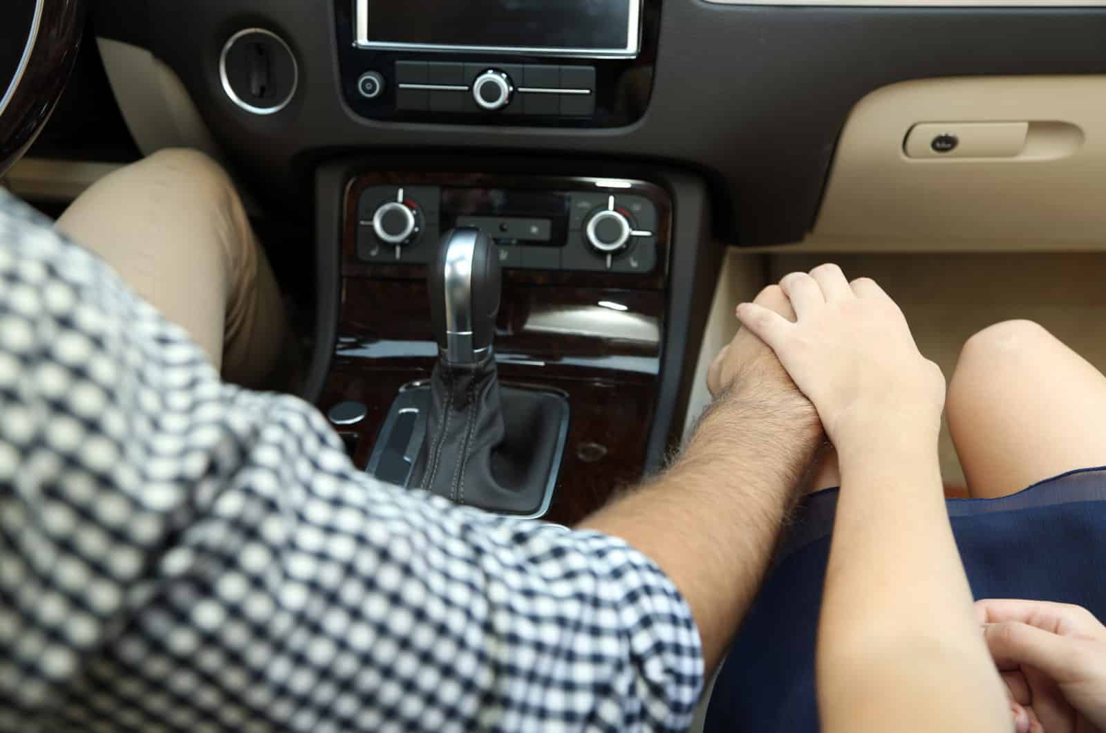 man with his hand on woman's thigh while driving