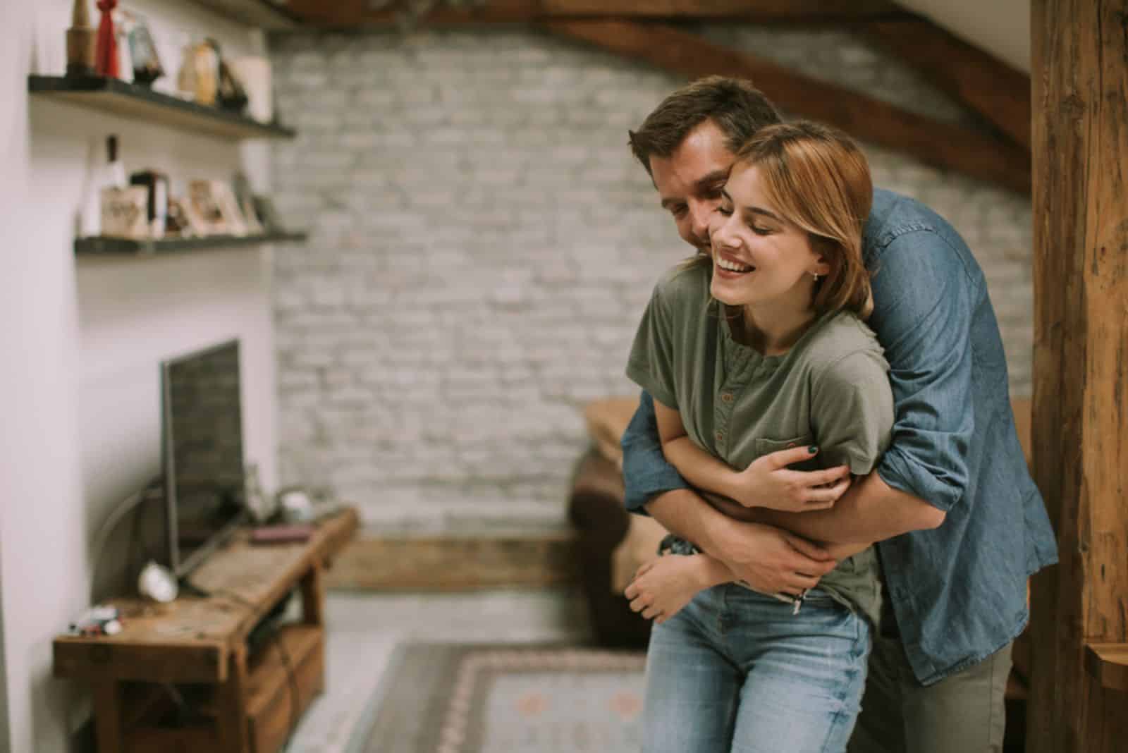 Young man and woman hugging standing at home