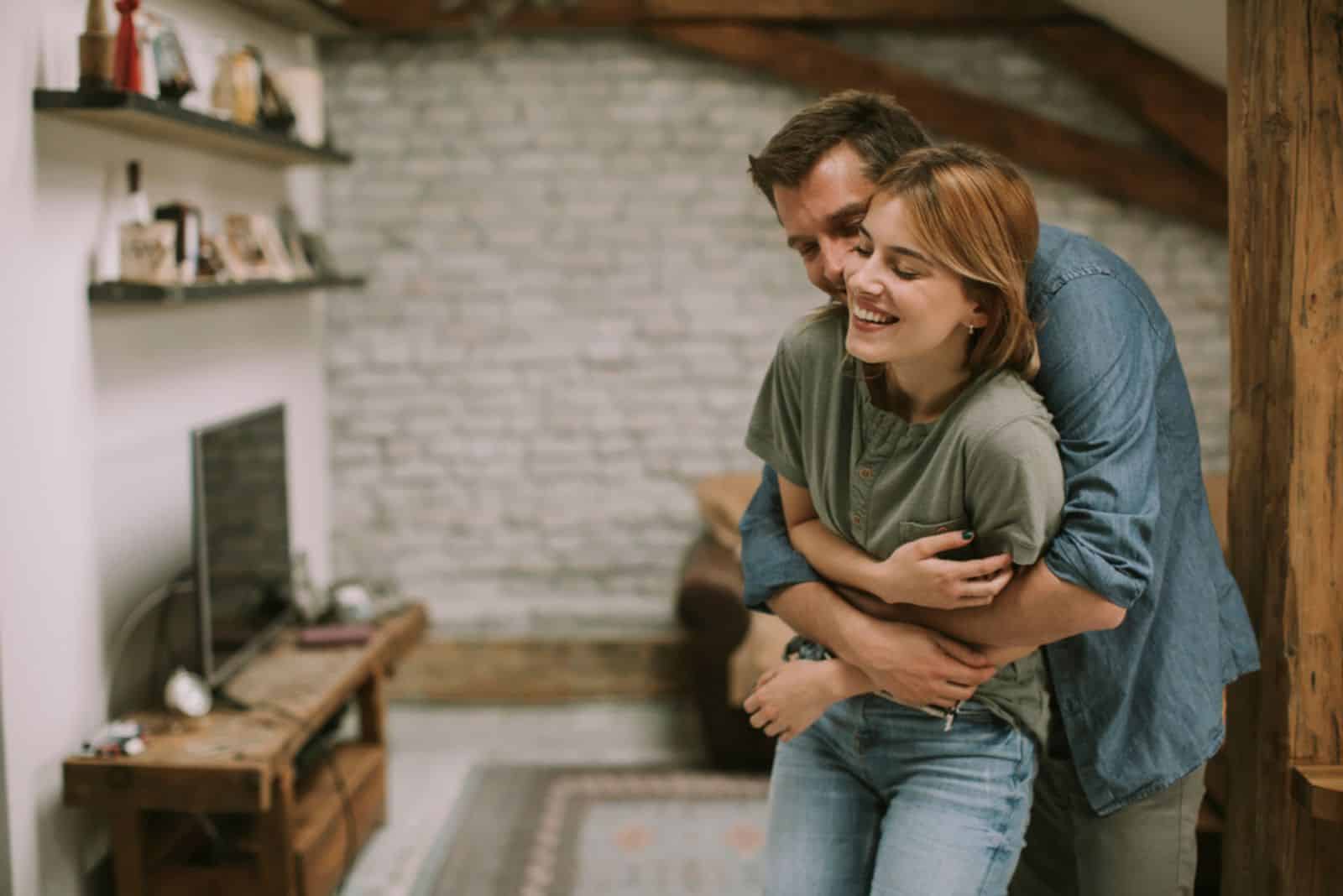 Giovane uomo e donna che si abbracciano in piedi in casa