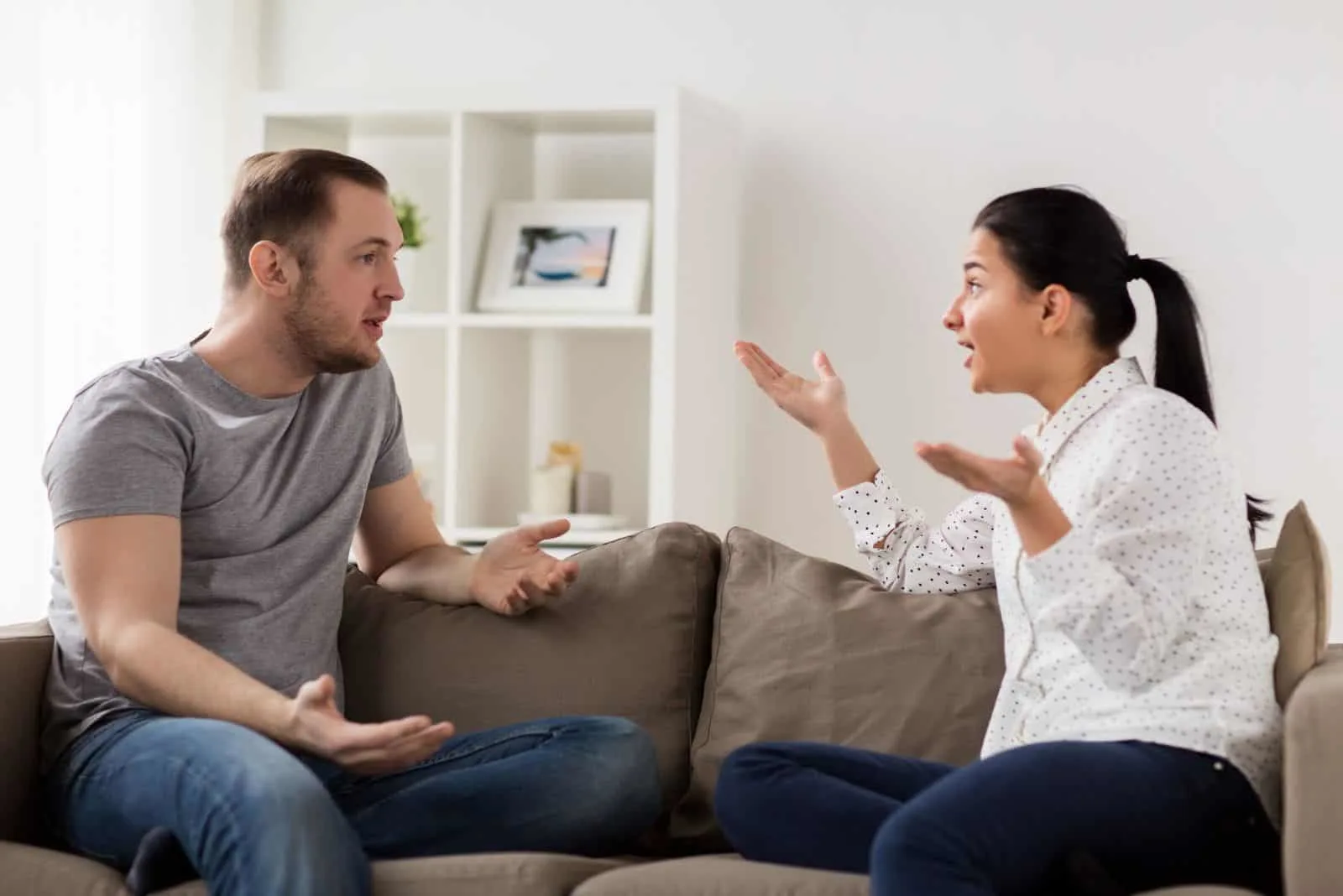a man and a woman are sitting on the couch and arguing