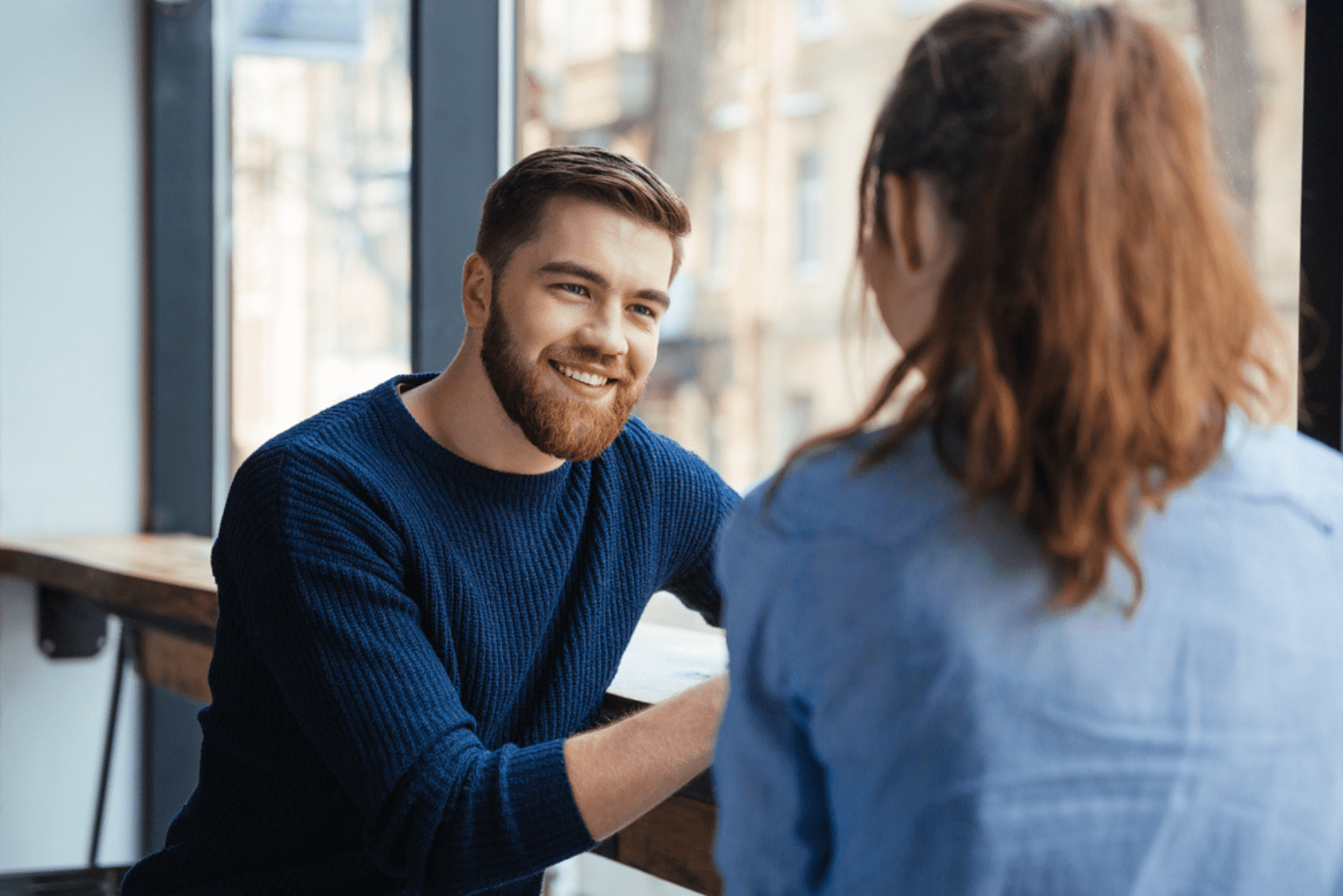 um homem sorridente está a falar com uma mulher num café