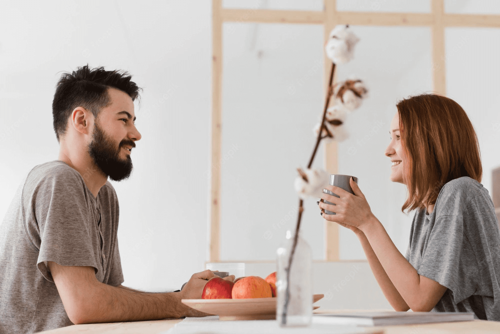 a smiling woman is sitting in the kitchen with a man and they are talking