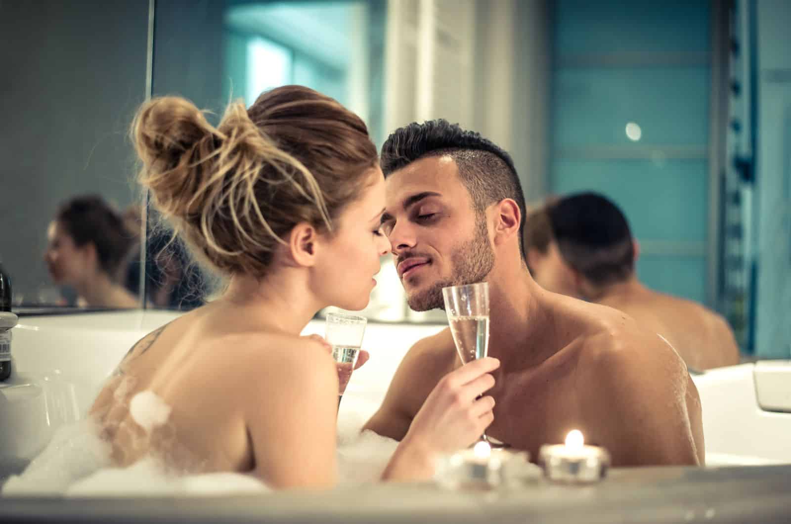 uomo e donna che si godono la vasca da bagno e bevono champagne