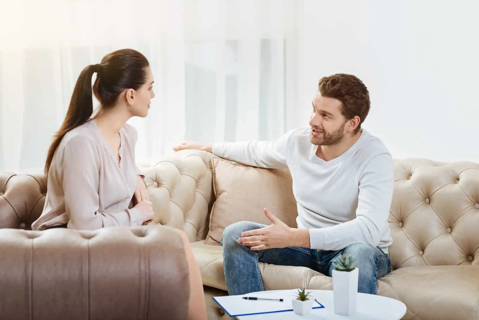man and woman sitting on sofa talking
