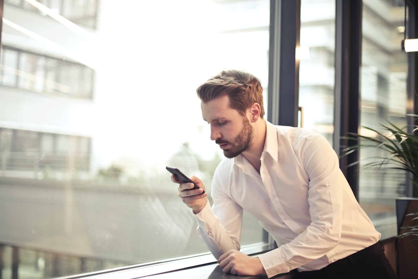 man in a white shirt using smartphone