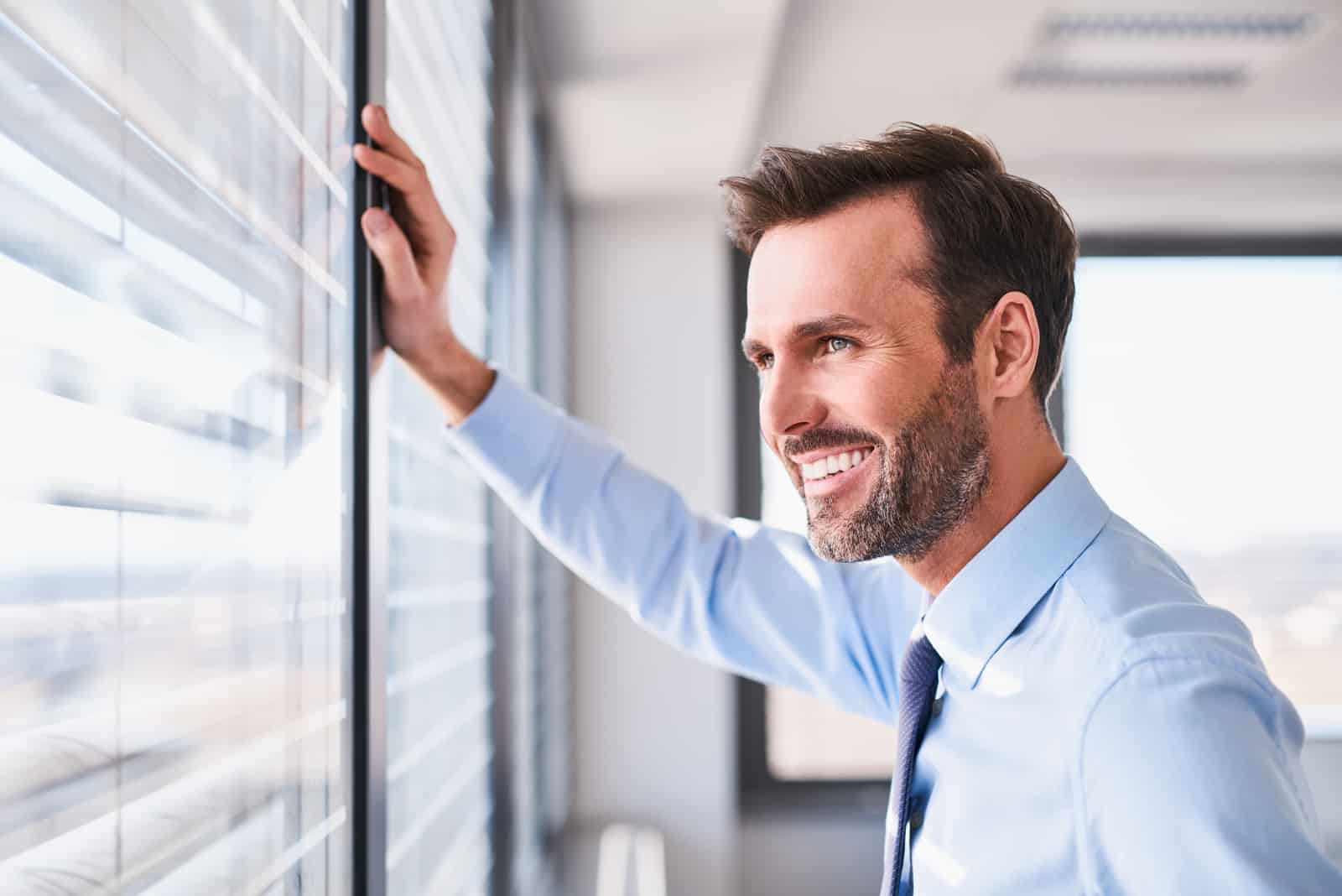 smiling man looking through window in the office
