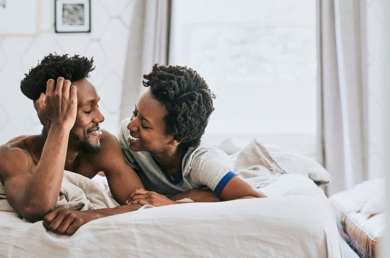 mulher e homem na cama a sorrir um para o outro enquanto se ligam