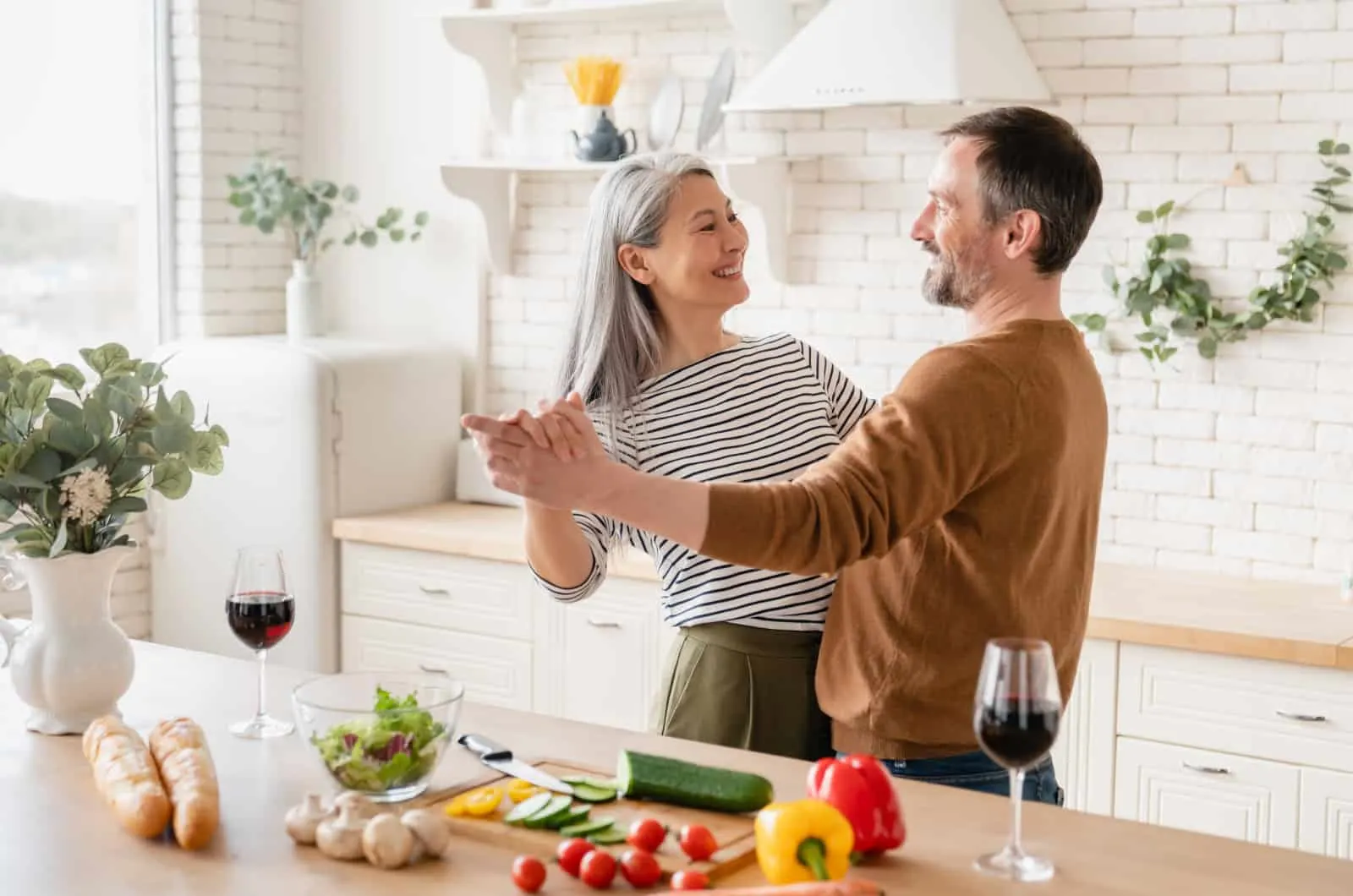 woman dancing with a man in the kitchen enjoying his company