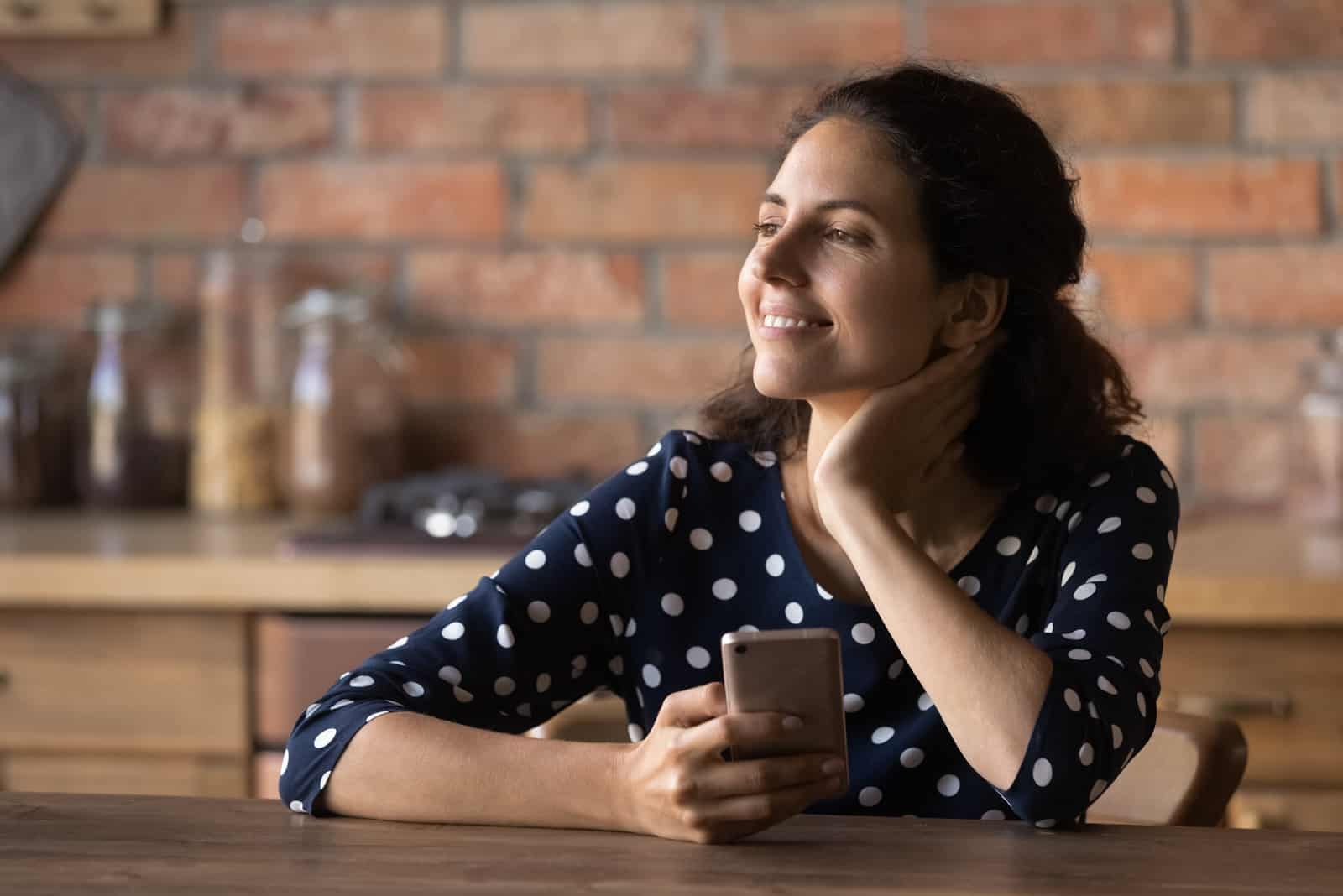 mulher a segurar o telemóvel e a sorrir