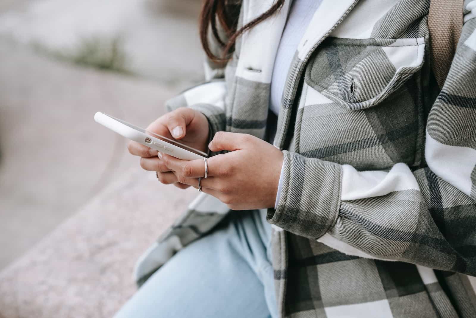 woman in a plaid shirt types on phone