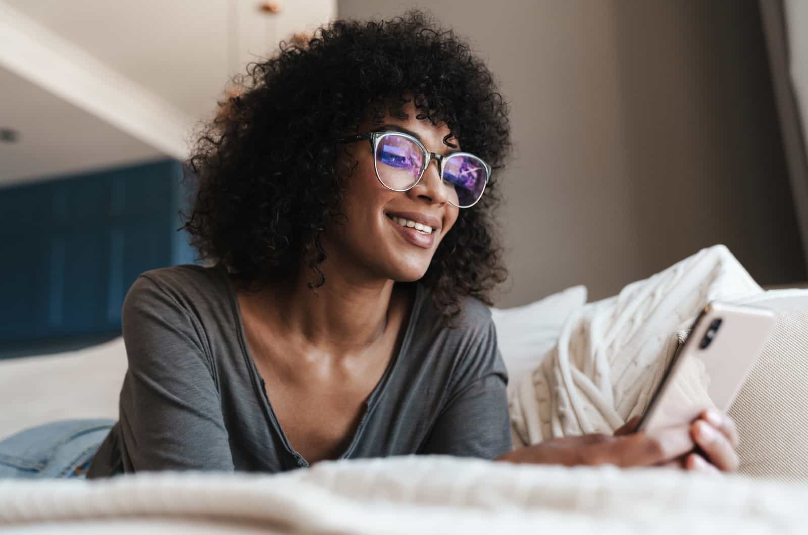 woman with curly hair texts on phone