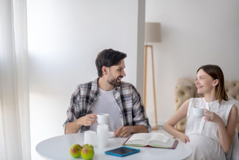 a smiling pregnant woman is sitting at the table with a man