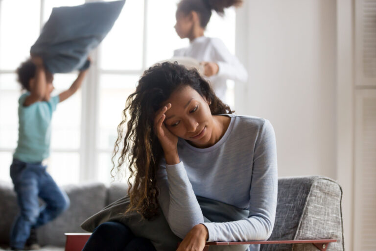 madre single stressata e preoccupata mentre i suoi figli giocano sullo sfondo