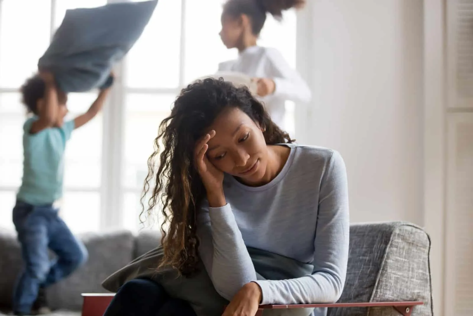 stressed single mother worried while her children play in the background