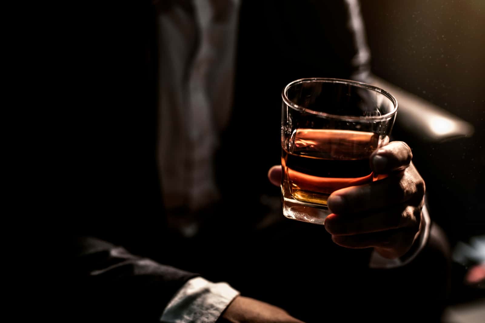 Primo piano di uomini d'affari con in mano un bicchiere di whisky