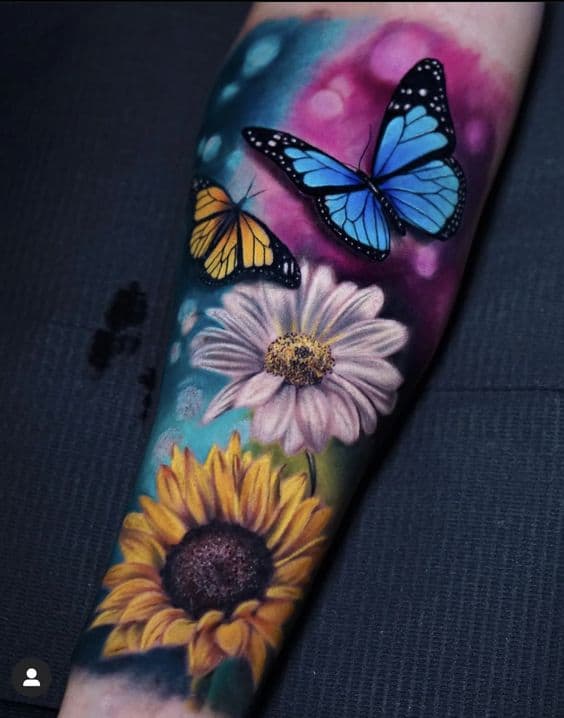 Tatuaggi colorati da donna con farfalle e fiori nella parte inferiore del braccio