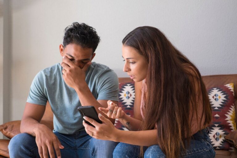 mujer disgustada mostrando a hombre teléfono móvil