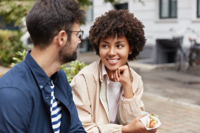 a woman with frizzy hair is sitting next to a man and they are talking