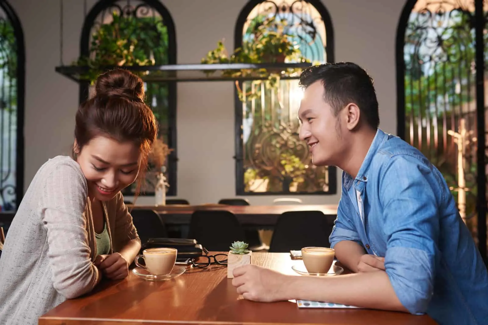 Side view portrait of loving Asian couple meeting in cafe for date