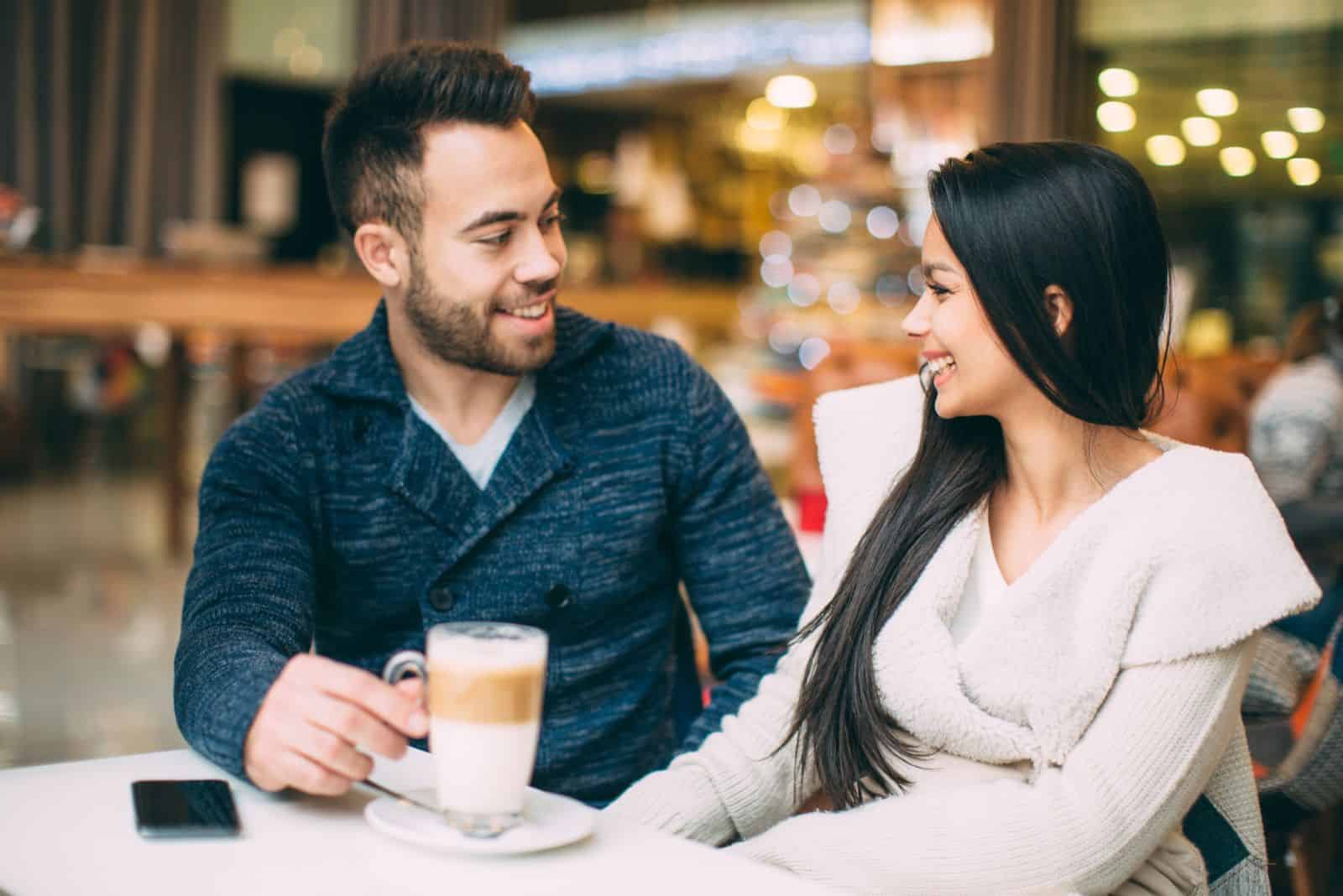 una coppia di innamorati è seduta in un caffè e sta parlando
