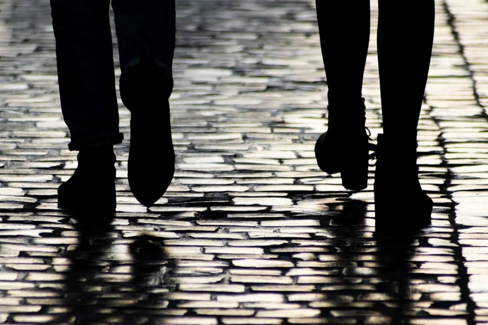 Two pedestrians walking down on evening street.