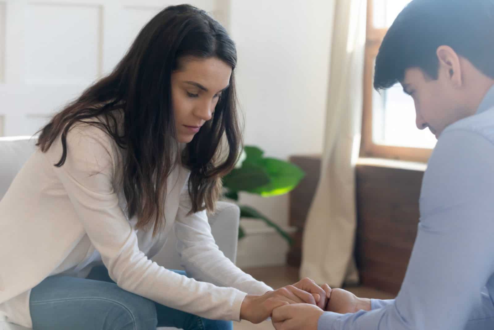 Unhappy young couple hold hands