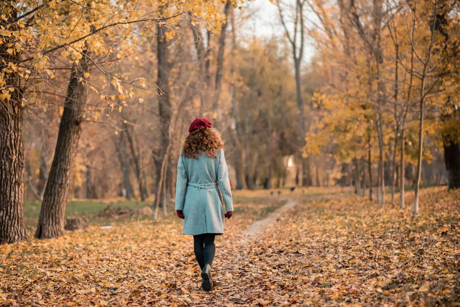 a girl with a gray coat is walking in the forest