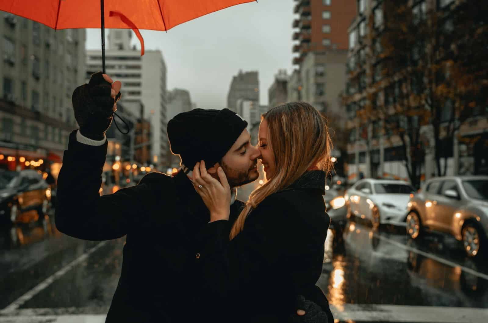 coppia che si bacia mentre l'uomo tiene l'ombrello