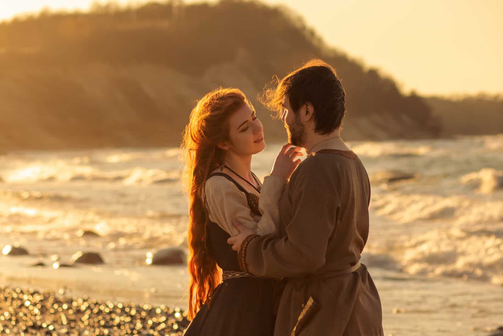 pareja vestida abrazándose en la orilla del mar