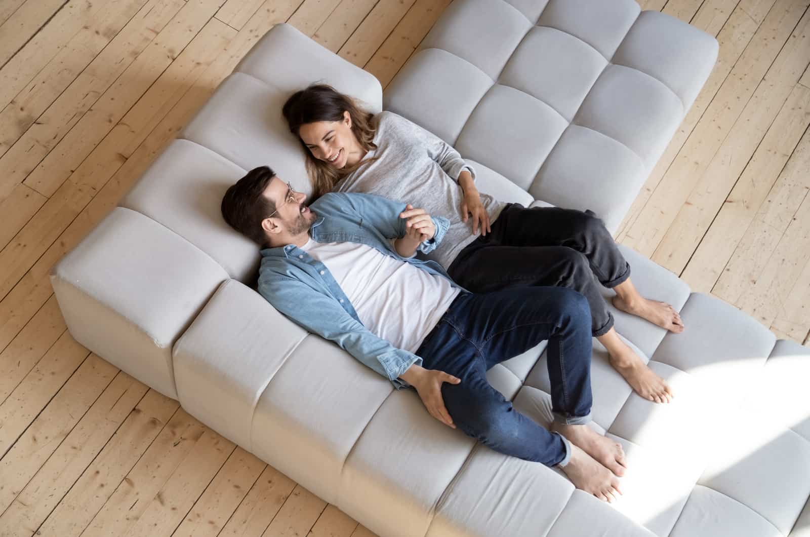 casal feliz deitado num sofá branco