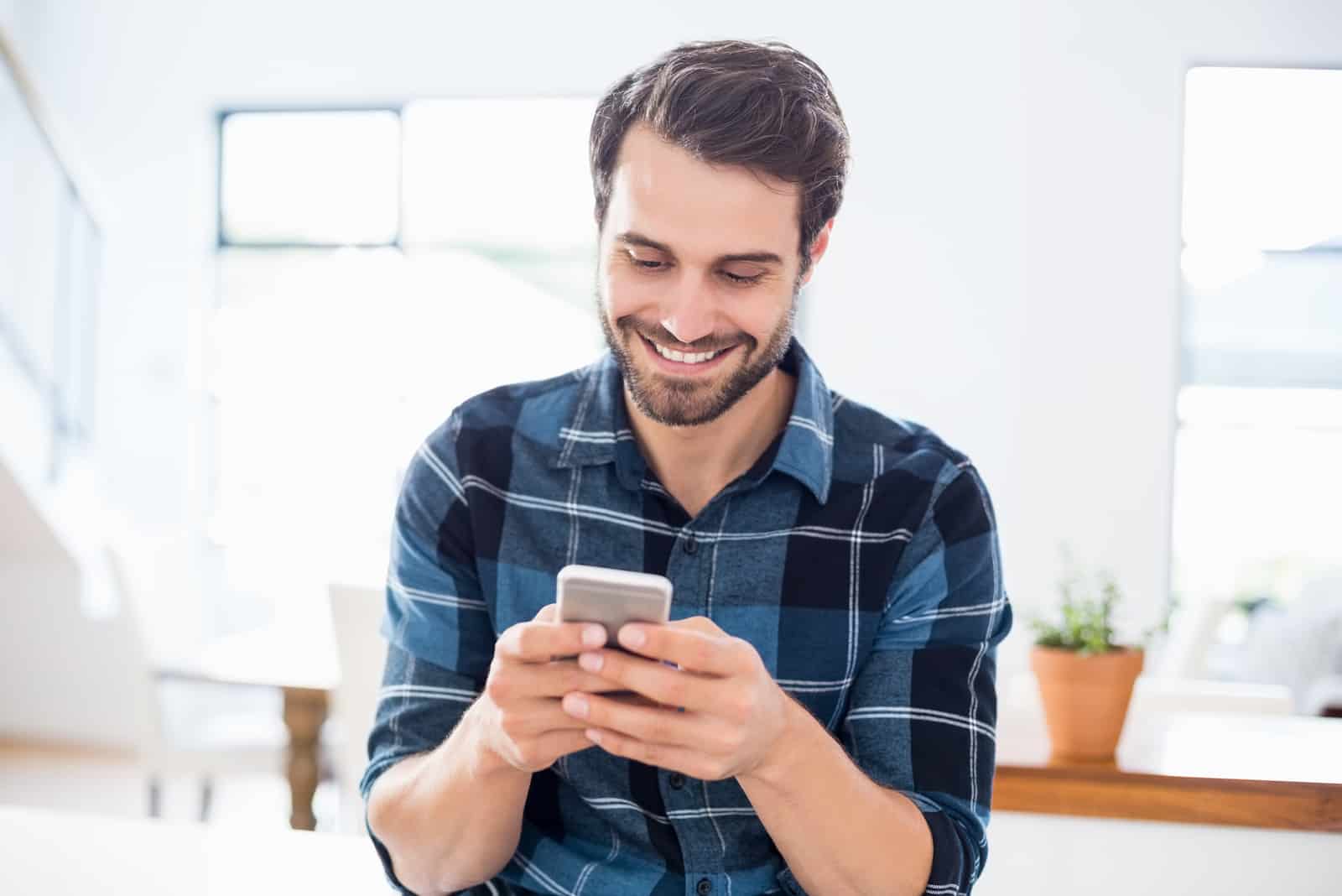 man texts on phone and smiles