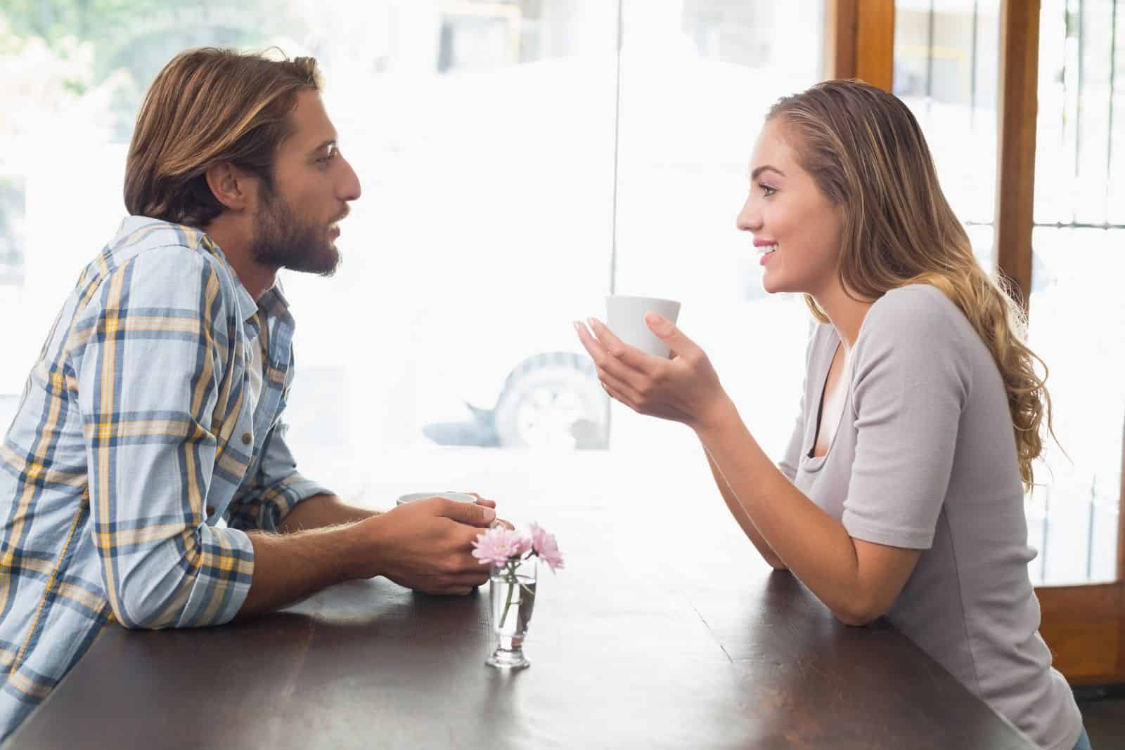smiling man and woman sit and talk over coffee