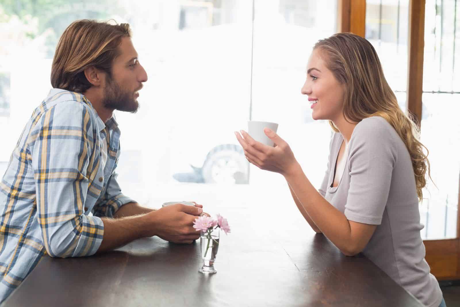 homem e mulher sorridentes sentam-se e conversam durante um café