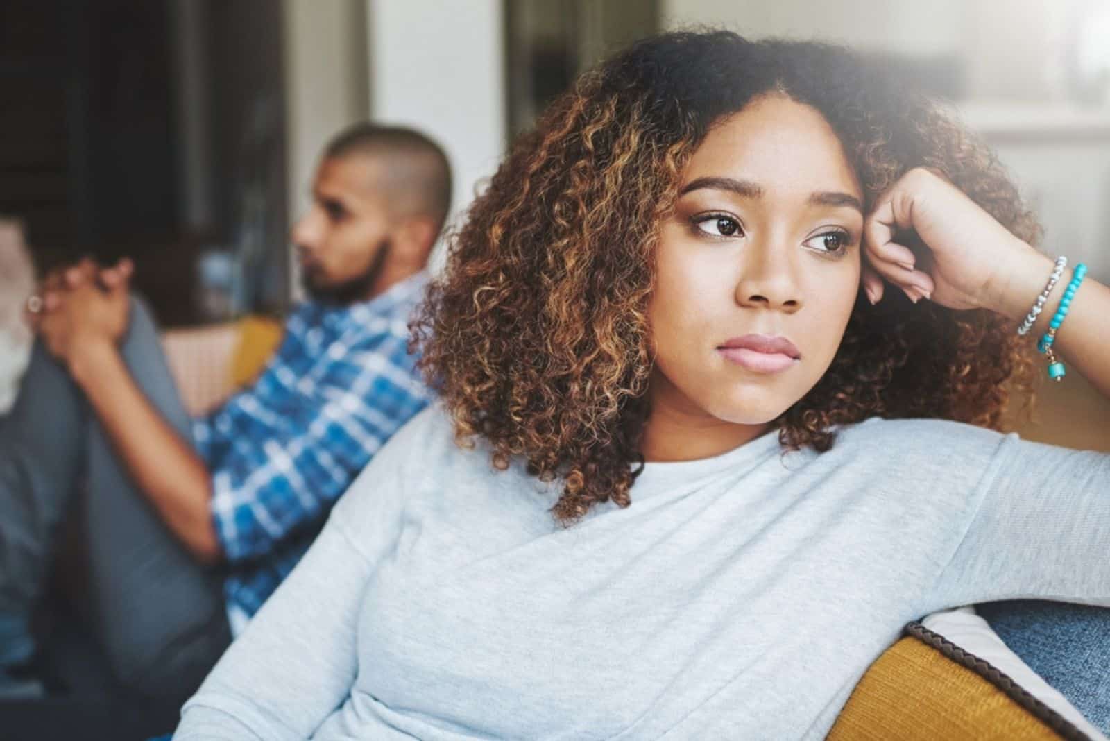 stressed couple sitting on a sofa together after arguing