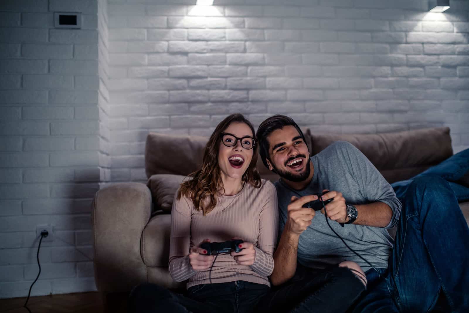 young couple playing video games at home at night.