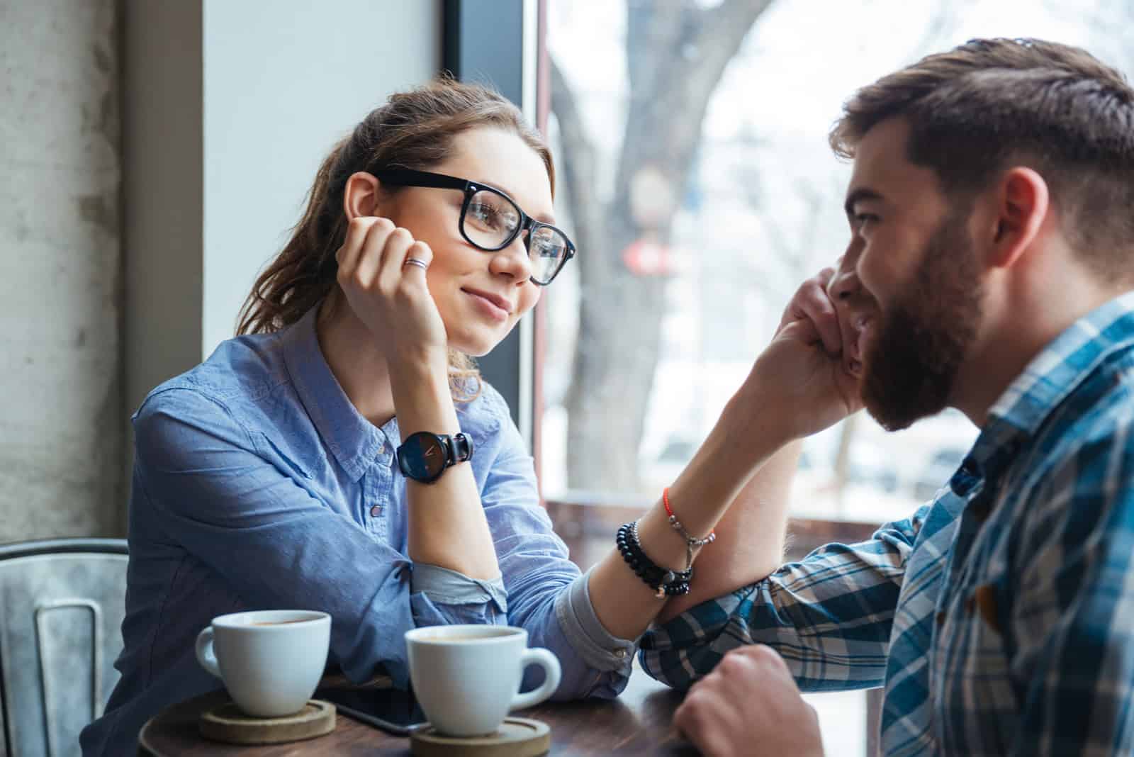 young woman looking at man while sitting at cafe