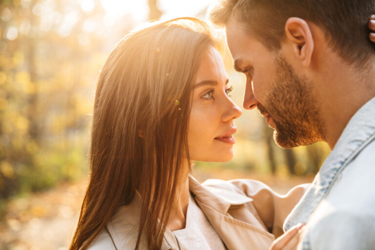 Primer plano de una bella pareja de jóvenes enamorados abrazándose mientras pasan el tiempo en el parque otoñal.