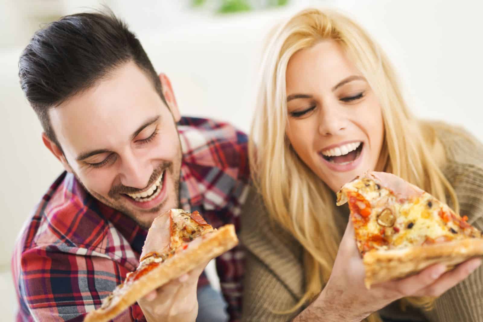 a man and a woman are eating pizza