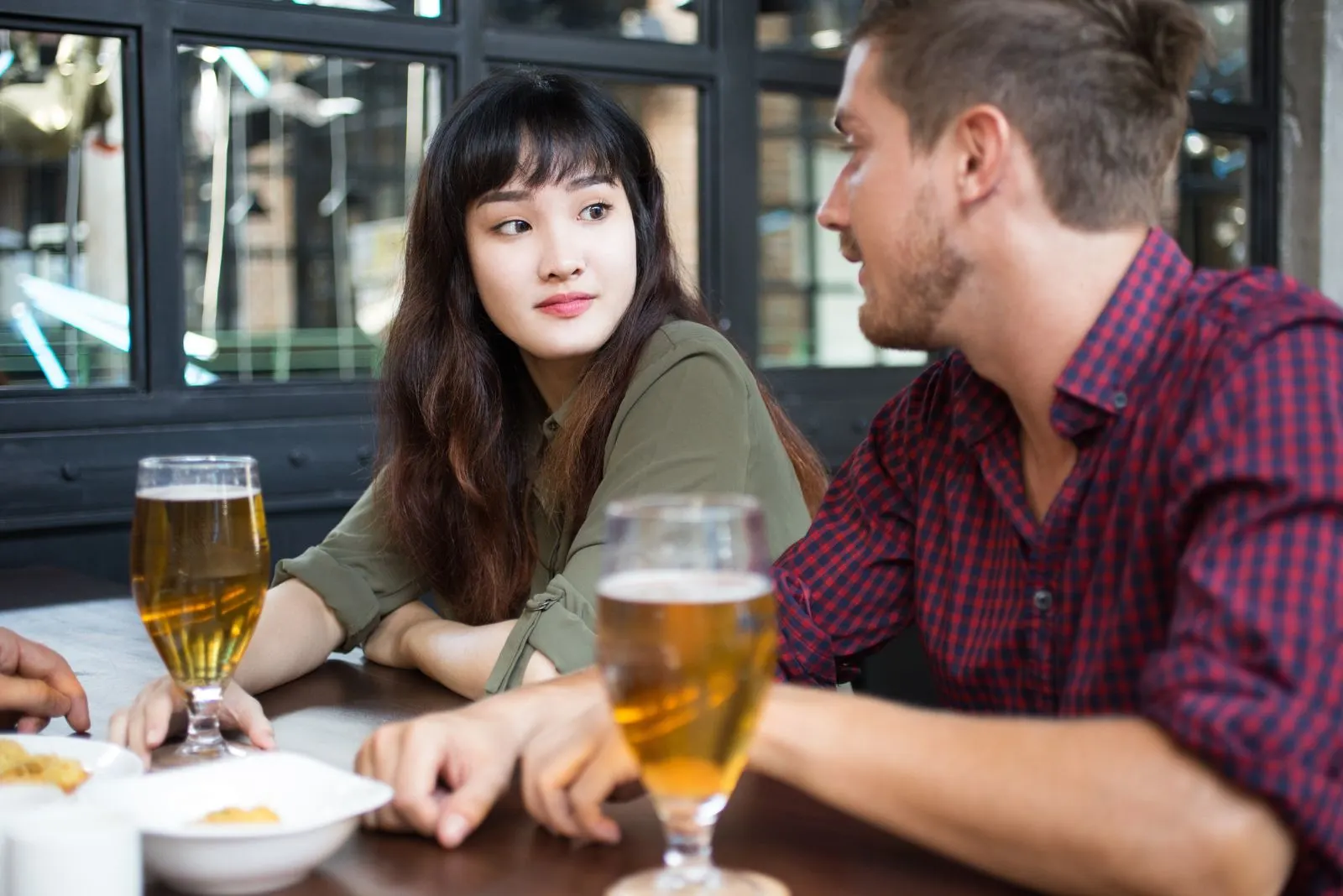 a man and a woman are sitting at the table and talking over beer