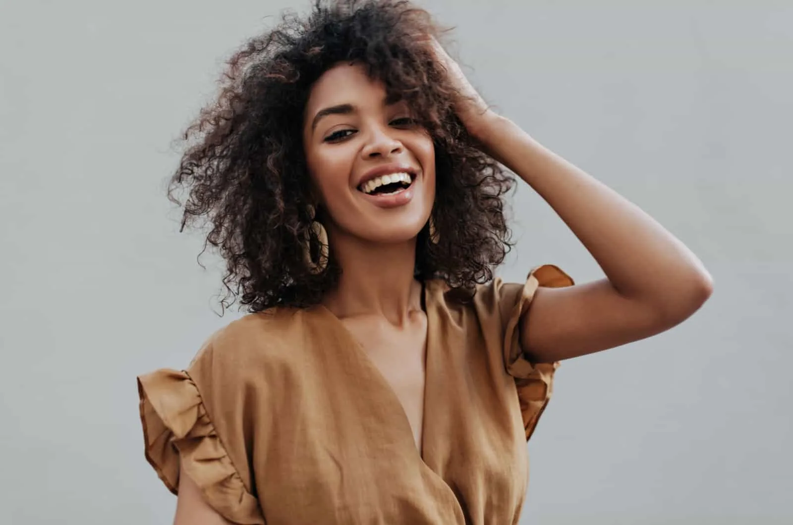 beautiful curly haired woman smiles and poses for camera