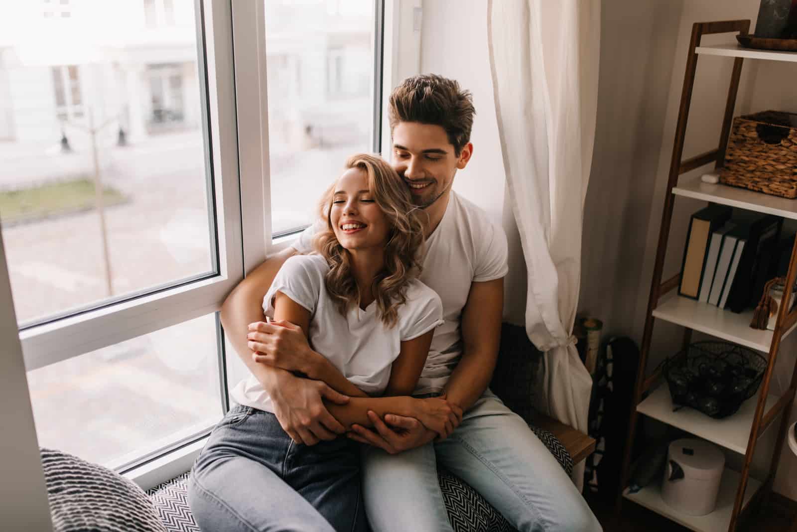 couple hugging in front of window