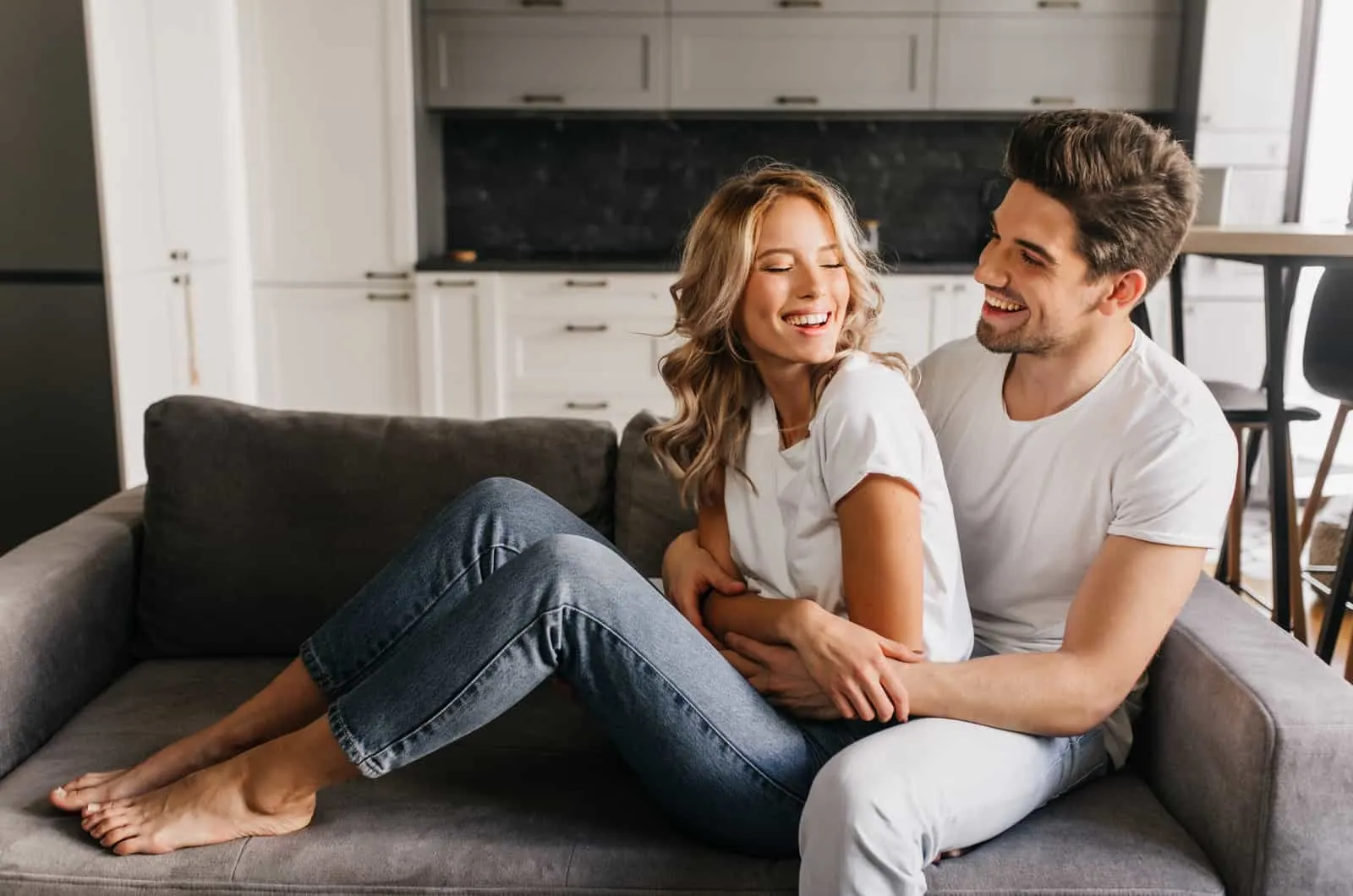 couple sit on a couch together and cuddle