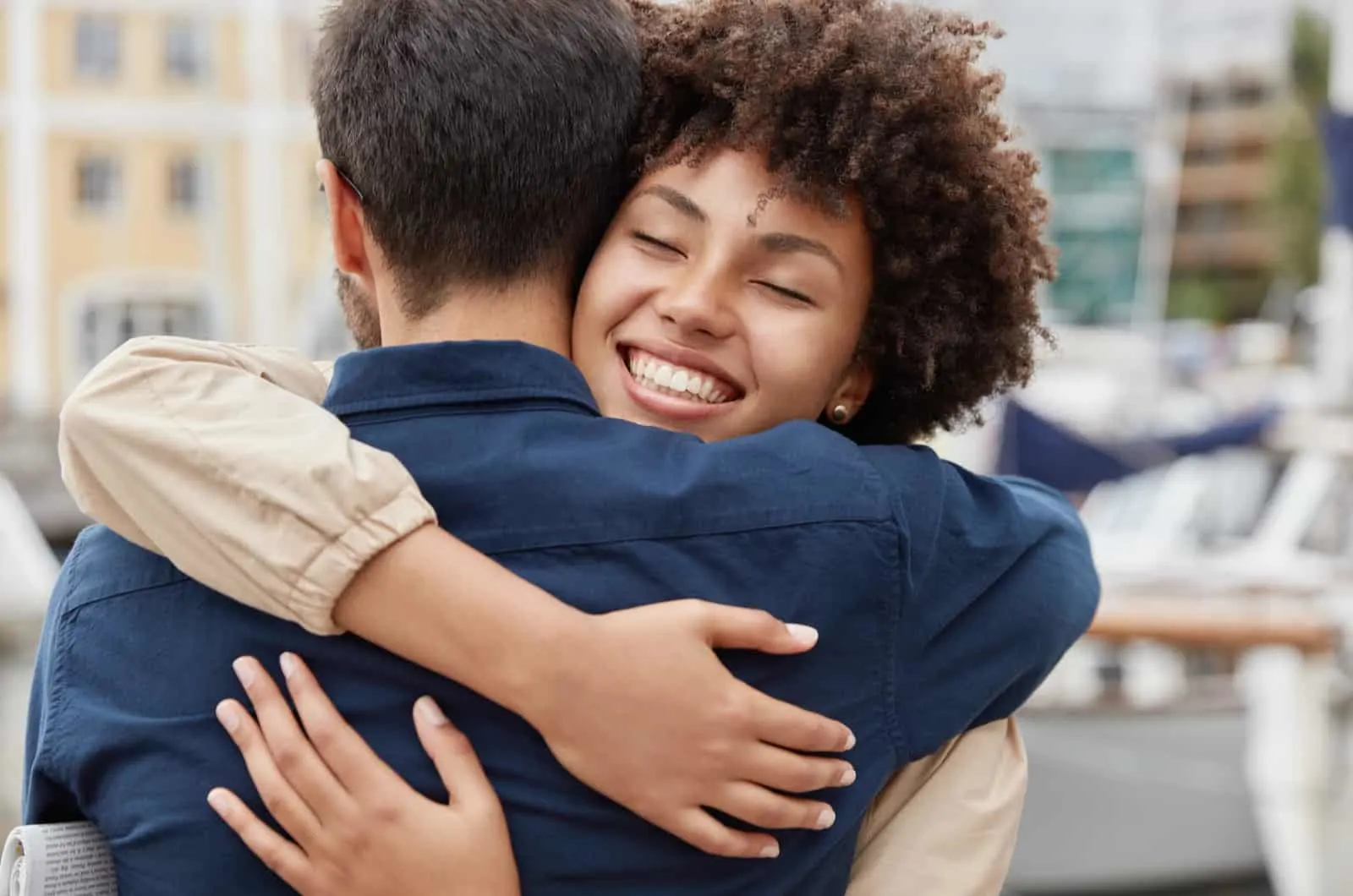 curly haired woman hugs her boyfriend and smiles